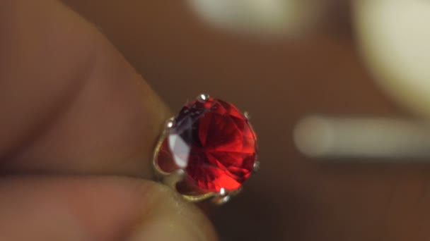 A professional jeweler polishes a red gem on a gold ring using a special tool. — Stock Video