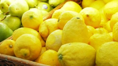 Genç çekici bir kadın karantina sırasında marketten olgun organik limon topluyor. Genç bir kadın markette organik limon seçiyor. Koruyucu eldiven giymiş genç bir kadının yakın çekimi.
