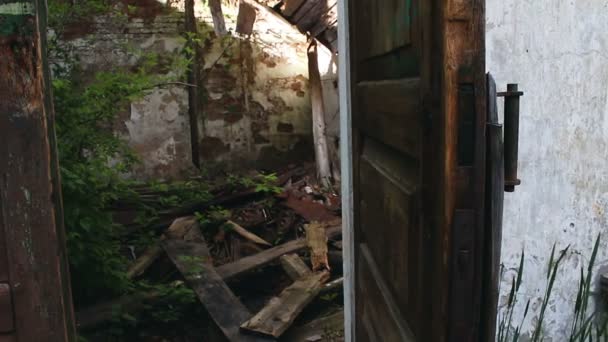 Μια παλιά πόρτα σε ένα εγκαταλελειμμένο κτίριο κλείνει από μόνη της. Η παλιά πόρτα ενός εγκαταλελειμμένου και κατεστραμμένου σπιτιού. — Αρχείο Βίντεο