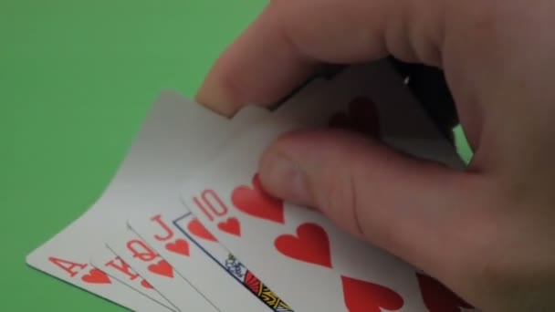 Φλος ρουαγιάλ στα χέρια ενός επαγγελματία παίκτη πόκερ. Ο παίκτης πόκερ ελέγχει τα χαρτιά του πριν αυξήσει το στοίχημα. Ένας επαγγελματίας παίκτης πόκερ έχει Hearts Flush Royal. Η έννοια του τζόγου. Α — Αρχείο Βίντεο
