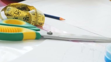 Genç bir moda tasarımcısının eli, yeni bir elbise modelini kesmekle meşgul. Moda tasarımcısı yeni bir elbise tasarlıyor. Genç kadın moda tasarımcısı...