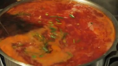 Gerçek Ukrayna çorbası bir tencerede pişirilir. Şef Ukrayna çorbası hazırlıyor. Aşçı Ukrayna borsch 'unu bir kaşıkla karıştırıyor..