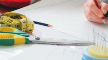 Moda tasarımcısı yeni bir elbise tasarlıyor. Genç bayan moda tasarımcısı yeni bir elbise modeli çiziyor. Genç bir kadın moda tasarımcısının eli çok yakın.