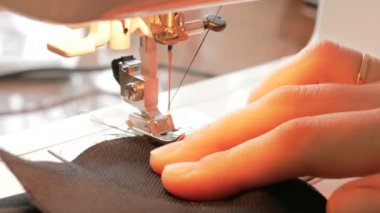 Genç ve çekici bir moda tasarımcısının ellerini yakın plan çekimde dikiş makinesine yeni bir elbise modeli dikiyor. İlgili genç ev hanımı dikiş makinesi kullanarak elbise dikiyor. Şunun yakın çekimi:
