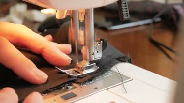 Karantina sırasında genç ve çekici bir kadın gönüllüyü yakından çekerek tıbbi koruyucu maskeler dikiyor. İlgili genç bir ev hanımı dikiş makinesi kullanarak koruyucu maskeler dikiyor. Şunun yakın çekimi: