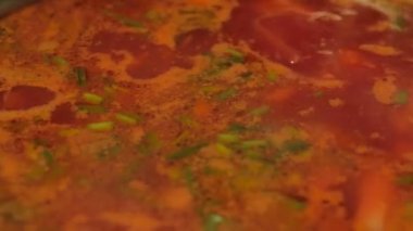 Gerçek Ukrayna çorbası bir tencerede pişirilir. Şef Ukrayna çorbası hazırlıyor. Aşçı Ukrayna borsch 'unu bir kaşıkla karıştırıyor..
