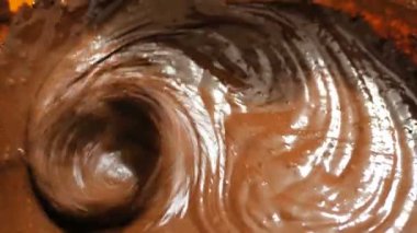 Şef pasta için çikolatalı kremayı mikserle karıştırıyor. Çikolata hamurunu browni yapmak için mikserle karıştıran bir şefin yakın çekimi..