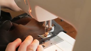 İlgili genç bir ev hanımı dikiş makinesi kullanarak koruyucu maskeler dikiyor. Karantina sırasında genç ve çekici bir kadın gönüllüyü yakından çekerek tıbbi koruyucu maskeler dikiyor. Şunun yakın çekimi: