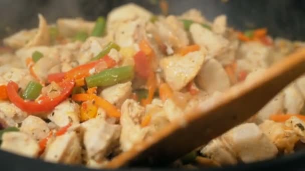The chef mixes chicken with vegetables in a frying pan. A professional chef prepares chicken with vegetables in a wok. — Stock Video