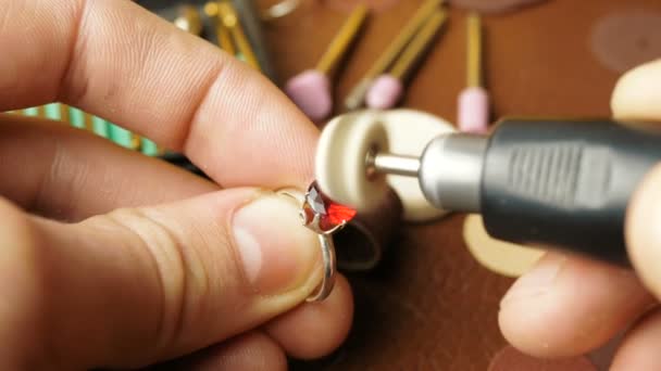 A professional jeweler polishes a red gem on a gold ring using a special tool. — Stock Video