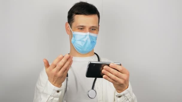 Um jovem médico dá uma consulta on-line a um paciente via chat por vídeo durante a quarentena. — Vídeo de Stock