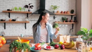 Mutlu, genç bir ev hanımı ahşap bir kaşıkta komik bir şekilde şarkı söyler ve mutfakta neşeyle dans eder. Çekici genç bir kadın, sevgili erkek arkadaşına yemek hazırlarken şarkı söyler ve dans eder.