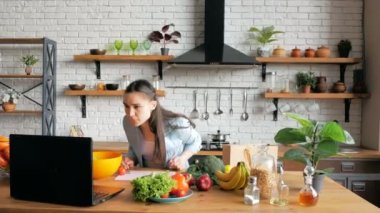 Mutfakta sebze salatası hazırlayan genç ve mutlu bir ev hanımı internetten tarifine bakıyor. Neşeli genç ev hanımı görüntülü bir sohbet sonrası salata hazırlar.