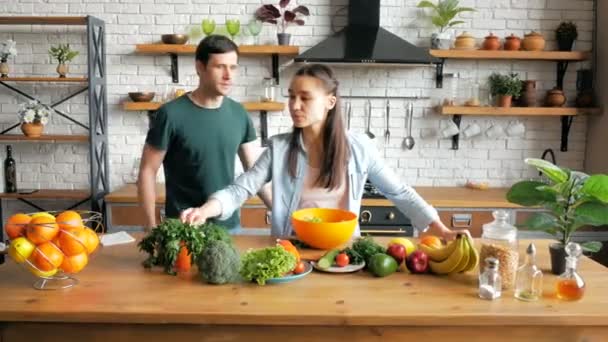 Jovem irritado grita com sua esposa, repreende por um mau jantar na cozinha de seu apartamento. Jovens casais de amantes estão brigando enquanto estão de pé na cozinha. Uma jovem bate no marido durante — Vídeo de Stock