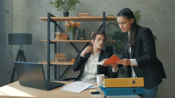 A young seo gives an assignment to his secretary.A young CEO solves business issues with his secretary. A young girl secretary brings documents to her boss for signature. — Stock Video