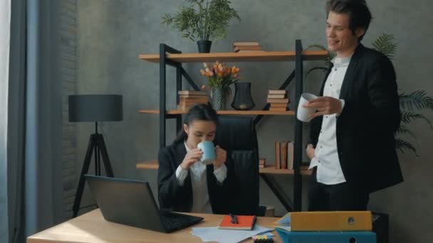 En ung VD med sin affärspartner dricker kaffe och löser affärsproblem i sitt företag. Kontorsanställda dricker kaffe på kontoret och diskuterar företagets utveckling — Stockvideo