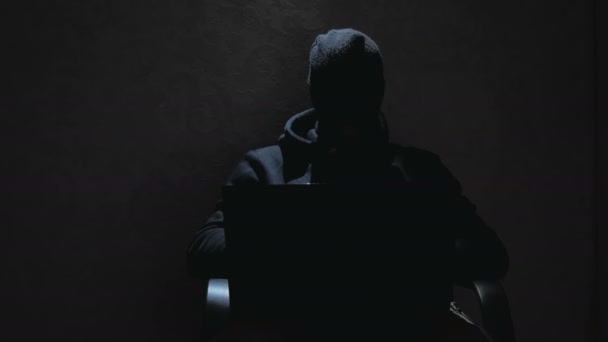 Anonymní hacker v černé mikině luští hesla a stahuje důležité databáze uživatelů internetu. Internetový hacker v černé kuklě sedí v křesle a krade data z notebooku. The — Stock video