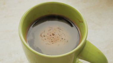 Masanın üzerinde bir fincan aromatik sıcak kahve var. Mutfak masasının üzerinde duran yeşil fincanda yeni demlenmiş Aromatik kahve. Mutfak masasının üzerinde sıcak aromatik doğal kahve stantları var..