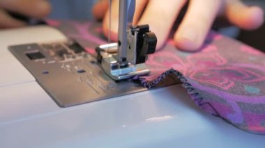 Karantina sırasında genç ve çekici bir kadın gönüllüyü yakından çekerek tıbbi koruyucu maskeler dikiyor. İlgili genç bir ev hanımı dikiş makinesi kullanarak koruyucu maskeler dikiyor. Şunun yakın çekimi: