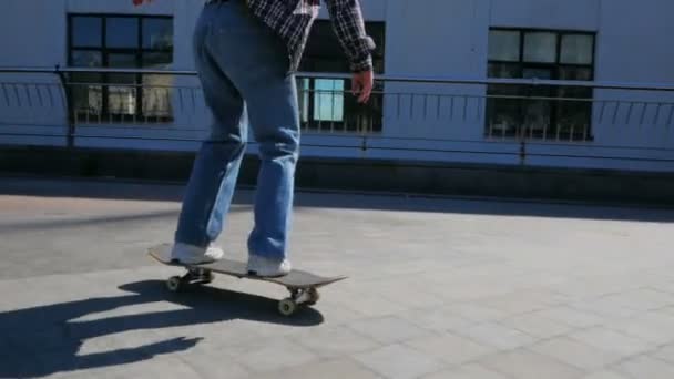 Jovem atraente está montando um skate. Um skatista profissional monta um skate ao longo da orla da cidade e faz acrobacias extremas. Jovem cara atraente está montando um skate. A — Vídeo de Stock