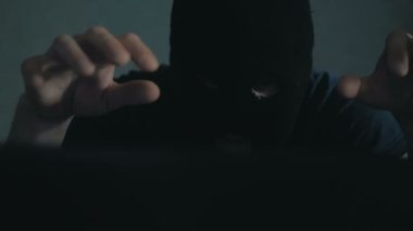 Siyah kar maskeli bir internet korsanı sandalyeye oturur ve laptoptan veri çalar. Siyah kapüşonlu bir hacker kurbanını telefonla arıyor ve veritabanının şifrelerini kırmakla tehdit ediyor.