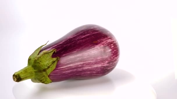 Zanahorias orgánicas jugosas maduras sobre un fondo blanco. Berenjena púrpura con rayas blancas gira sobre un fondo blanco. — Vídeo de stock