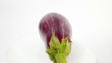 Beyaz çizgili mor patlıcan beyaz arka planda döner. Beyaz arka planda olgun, sulu organik patlıcan kesikleri..