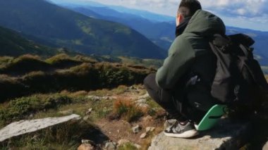 Genç gezgin uçurumun tepesinde otururken sıradağların manzarasından zevk alır..