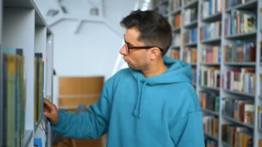 Gözlüklü genç bir milenyum öğrencisi bir halk kütüphanesindeki kitaplıklardan ilginç bir kitap seçer. Genç ve çekici bir öğrencinin portresi. Doğru kitabı arıyor.