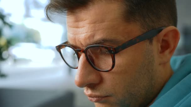 Young attractive businessman reads the news on a social network on his smartphone while sitting in a chair. Close-up shot of a young successful programmer wearing glasses, checks email on his — Stock Video