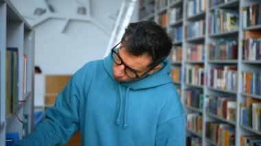 Gözlüklü genç bir milenyum öğrencisi bir halk kütüphanesindeki kitaplıklardan ilginç bir kitap seçer. Gözlüklü genç bir öğrenci sınava hazırlanmak için gerekli ders kitabını arıyor.