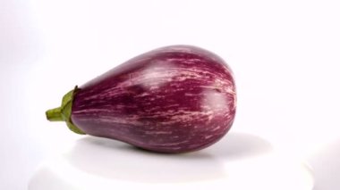 Beyaz çizgili mor patlıcan beyaz arka planda döner. Beyaz arka planda olgun, sulu organik patlıcan kesikleri..