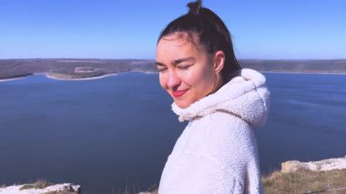 Güzel bir genç kız dağ gölü manzarasının tadını çıkarıyor. Yüksek kalite 4k görüntü