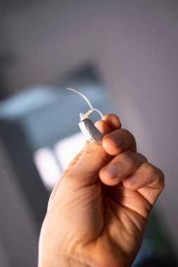 Modern dijital işitme cihazı 40 'lı yaşların ortasında 50' li yaşlarda bir adamın elinde.