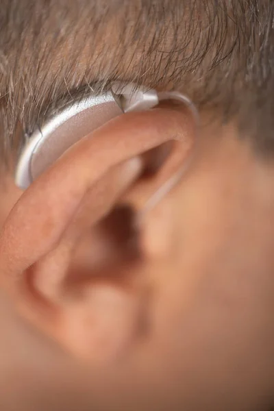 Modern digital hearing aid in ear of middle aged 40s 50s man