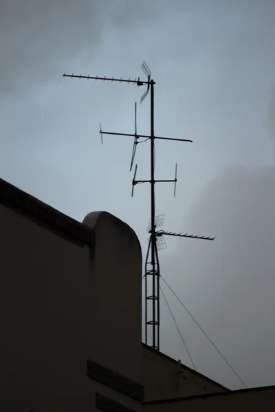 Телевізійна арійна антена на даху будівлі і сіре небо — стокове фото