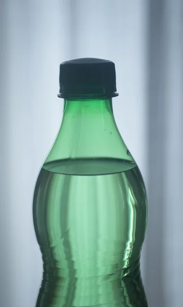 Geïsoleerde kunststof water groene fles blauwe achtergrond — Stockfoto