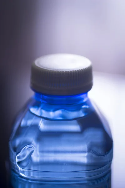 Geïsoleerde plastic waterfles duidelijke blauwe achtergrond studio opname — Stockfoto