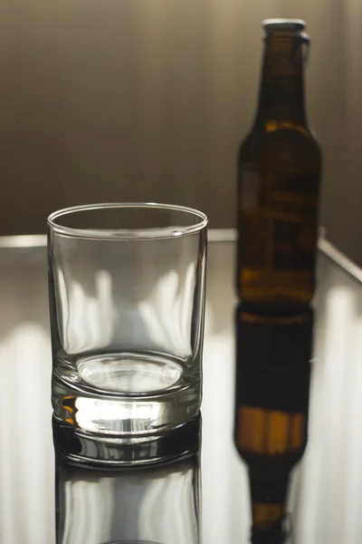 Fles bier en leeg glas op tafel — Stockfoto