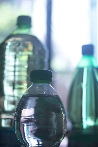 Plastic water bottles in window light — Stockfoto
