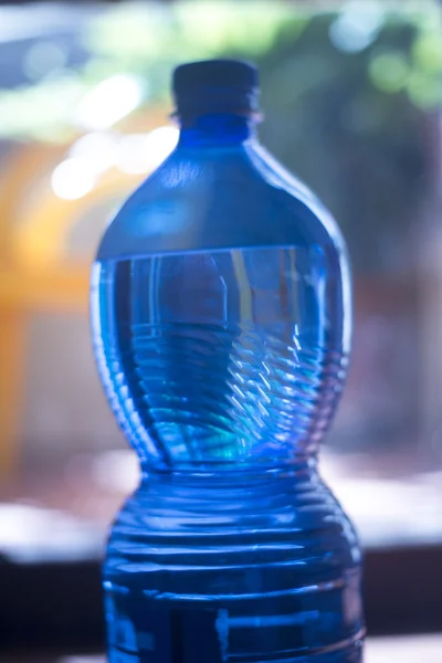 Plastová láhev s vodou v okně světlo — Stock fotografie