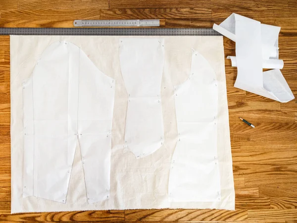 Top view of fixed paper pattern layouts of dress on calico fabric on wooden table at home — Stock Image Top View Fixed Paper Pattern Layouts Dress Calico Fabric Wooden Stock Photo
