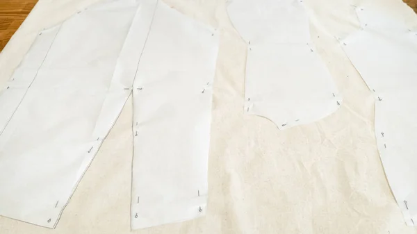 Fixed paper pattern layouts of dress on calico fabric on wooden table at home — Stock Image Fixed Paper Pattern Layouts Dress Calico Fabric Wooden Table Home Royalty Free Stock Photos