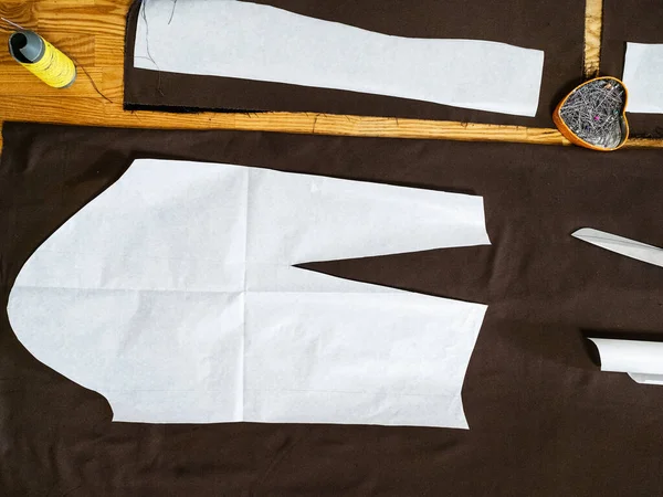 Top view of paper pattern layout of dress on brown fabric on wooden table at home — Stock Image Top View Paper Pattern Layout Dress Brown Fabric Wooden Table Royalty Free Stock Images
