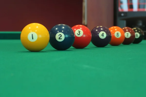 Yellow snooker ball with number one on it with other colorful balls placed in a row on a table - snooker game concept image — Stock Photo, Image