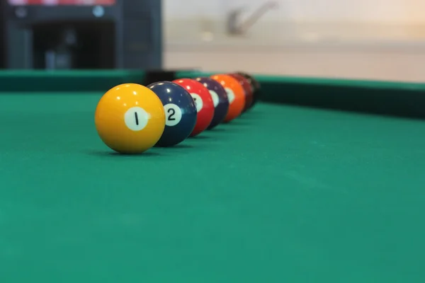 Yellow snooker ball with number one on it with other colorful balls placed in a row on a table - snooker game concept image — Stock Photo, Image