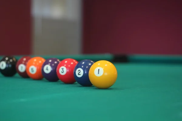 Palla da biliardo gialla con il numero uno su di esso con altre palline colorate poste in fila su un tavolo - immagine concetto di gioco da biliardo — Foto Stock