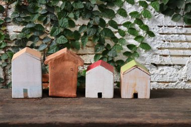 Doğası ve beyaz arka planı olan dört oyuncak model ev.