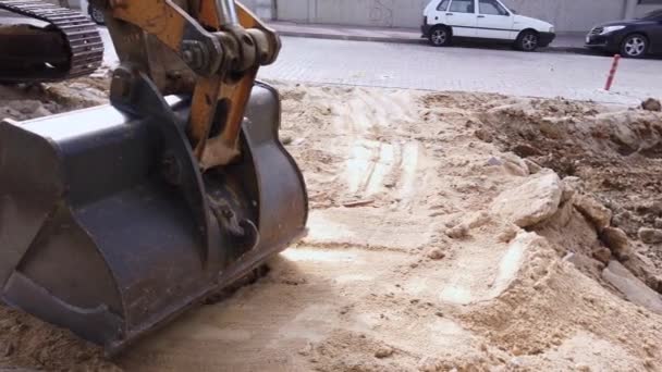 Road repair work. excavator metal bucket digs ground before laying asphalt — Stock Video
