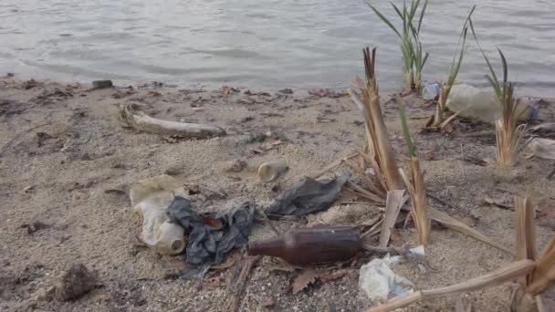 Un montón de residuos de plástico, placas, botellas rotas estériles fragmentos de latas de metal en la orilla — Vídeo de stock